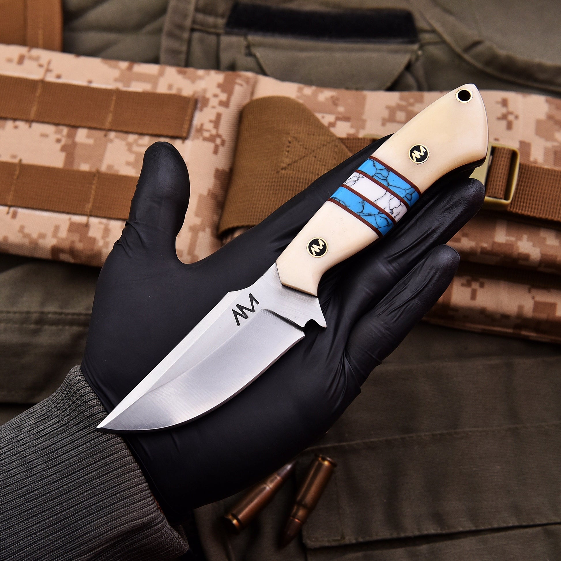 Knife held by a gloved hand with camouflage background