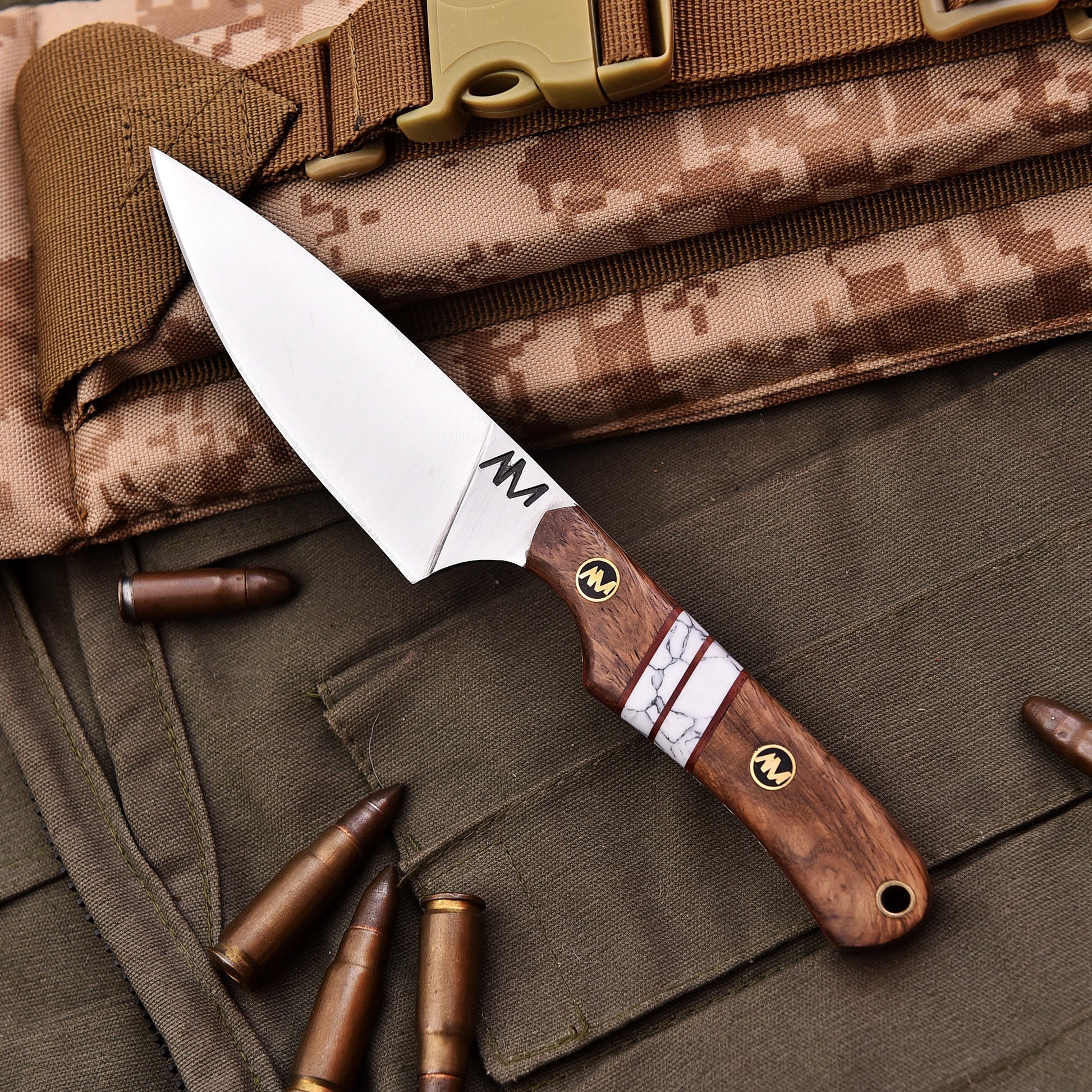 Knife with wooden handle on camouflage fabric with bullets