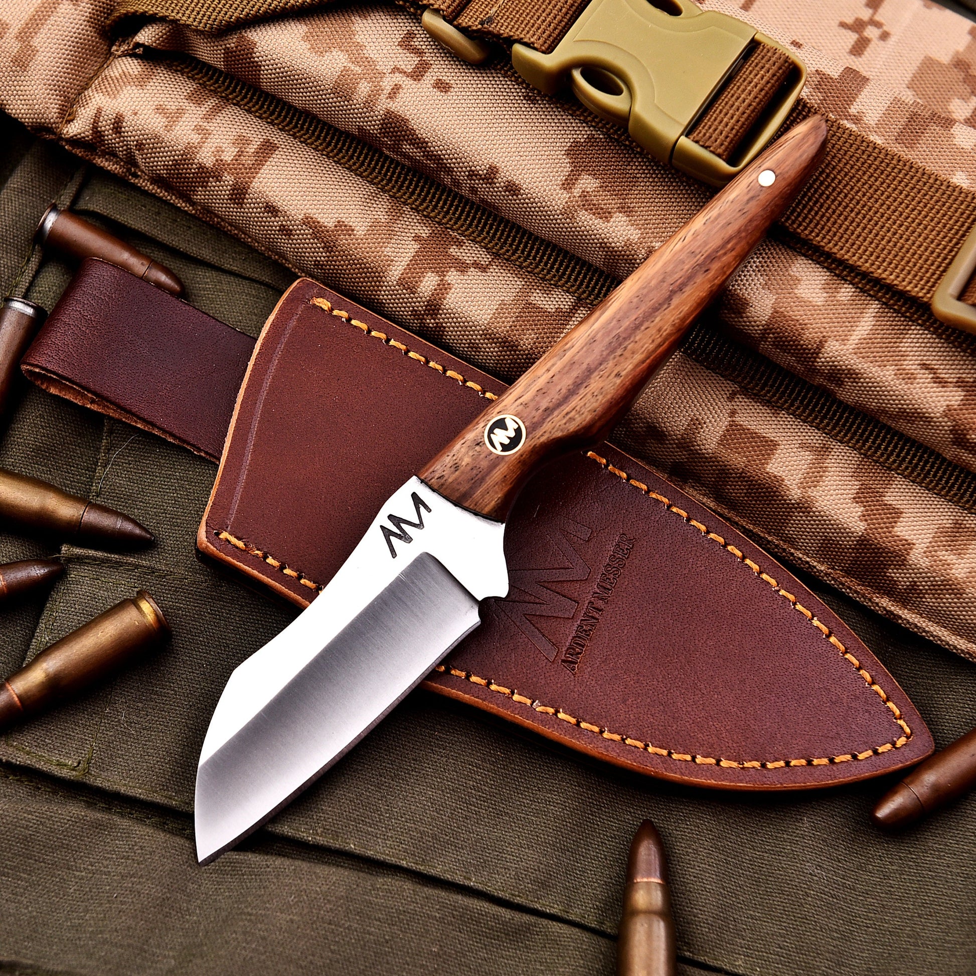 Knife with leather sheath on camouflage fabric with bullets
