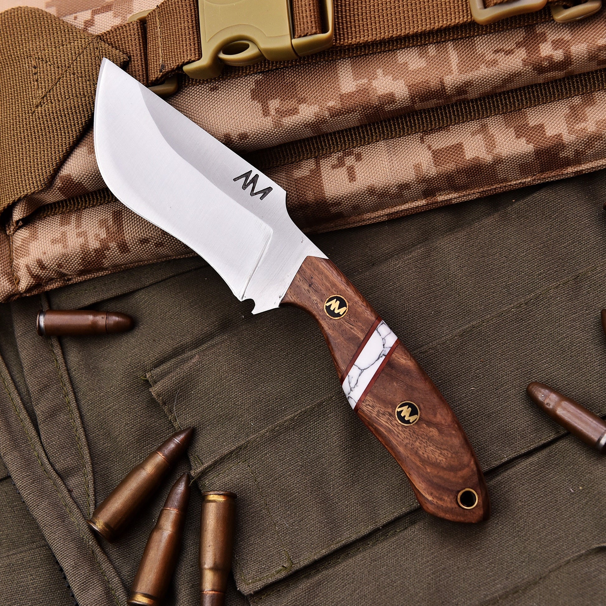 Knife with wooden handle and metal blade on camouflage fabric