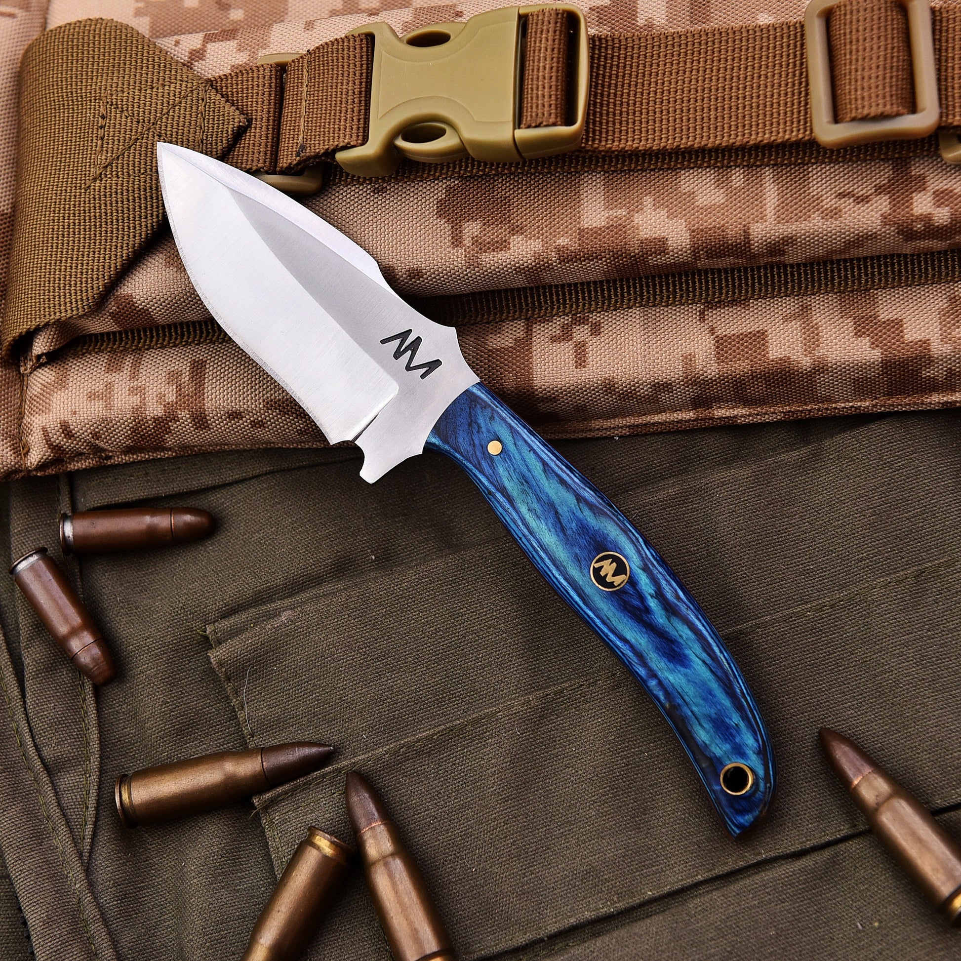 Knife with blue handle and brown sheath on camouflage fabric