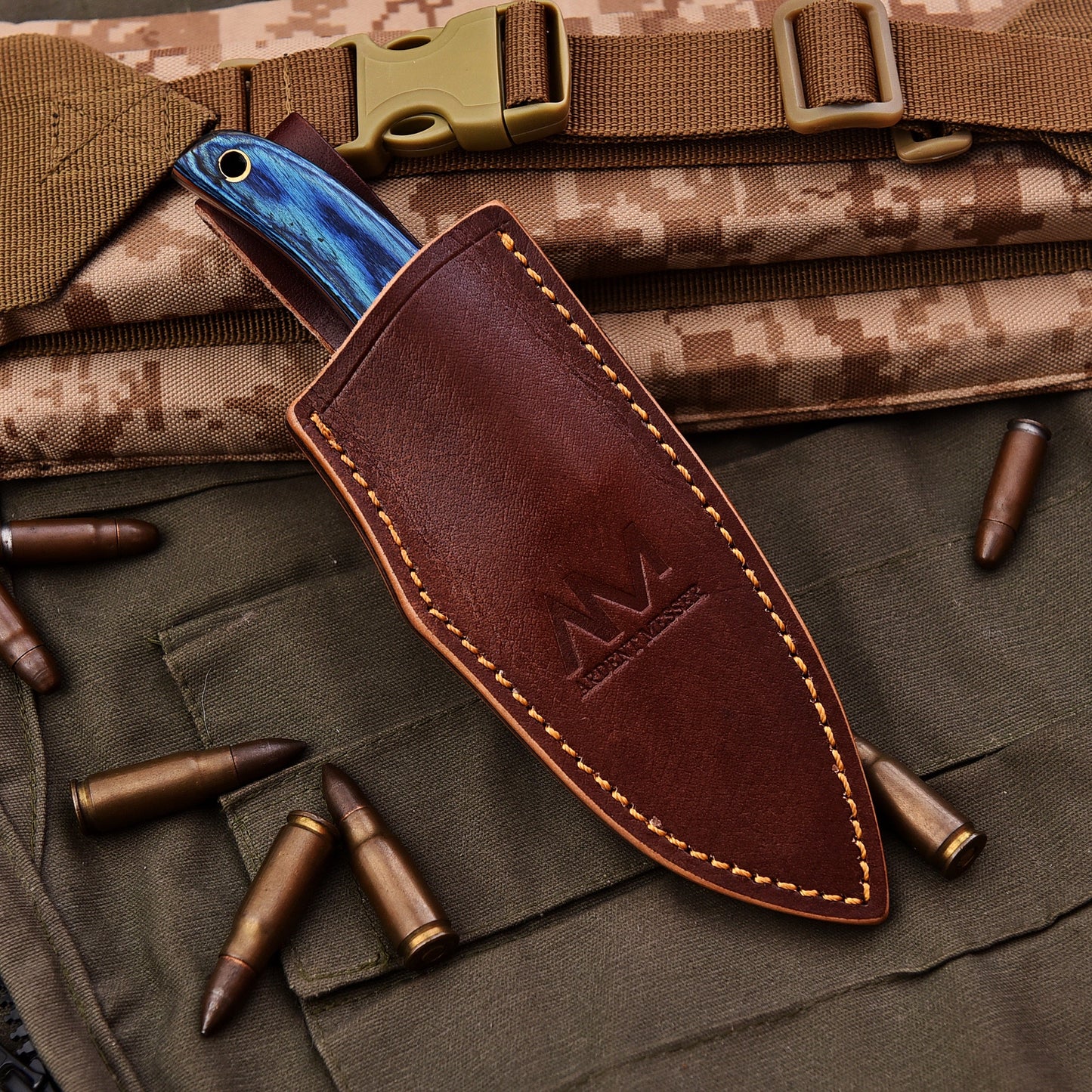 Brown leather knife sheath with blue blade on a camouflage background with bullets