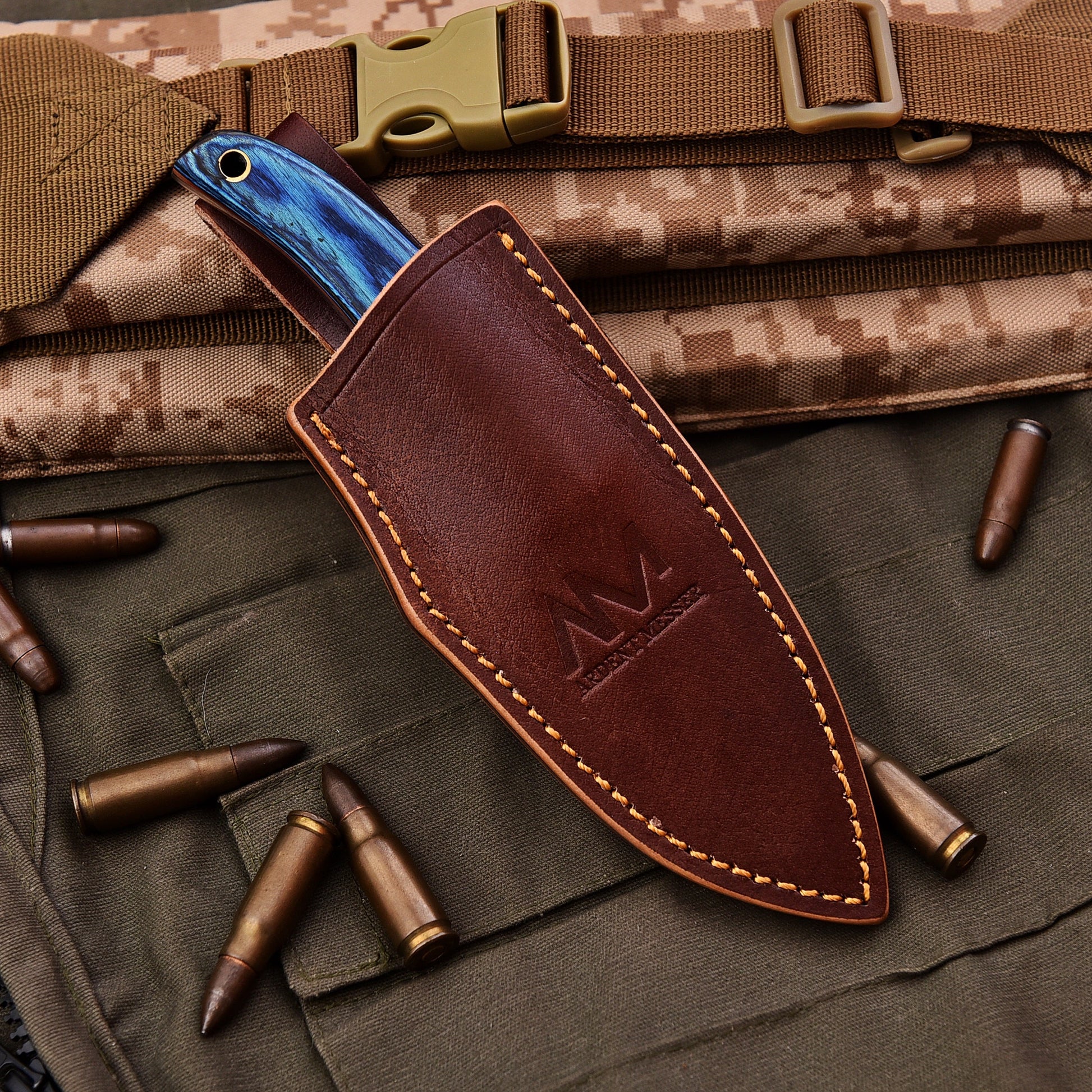 Brown leather knife sheath with blue blade on a camouflage background with bullets
