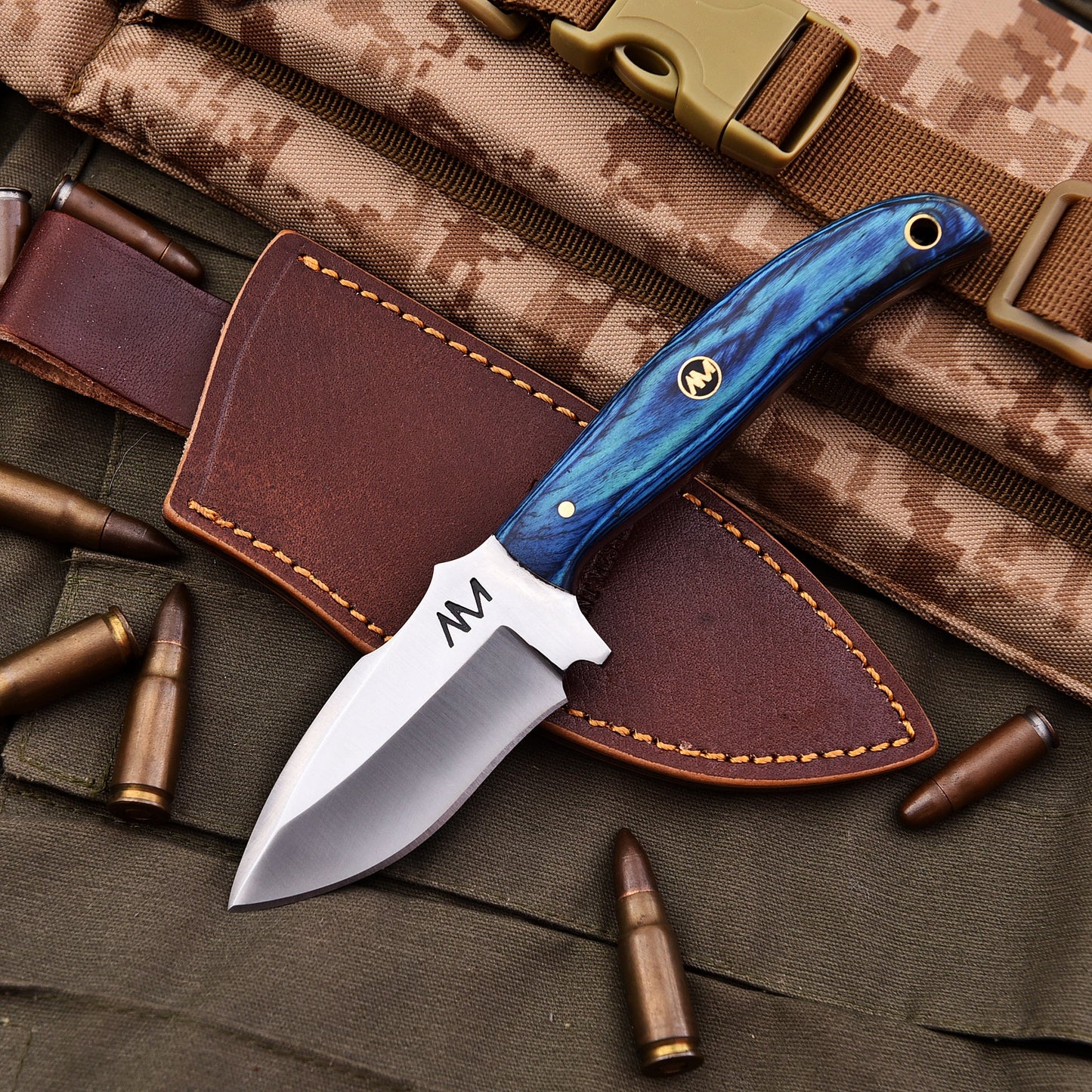 Knife with blue handle and leather sheath on camouflage fabric with bullets