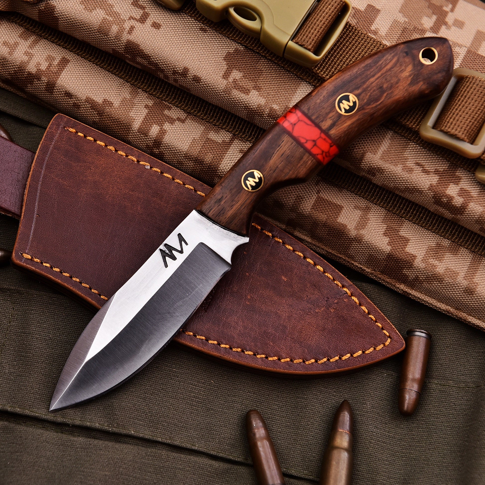 Knife with wooden handle and leather sheath on camouflage fabric background