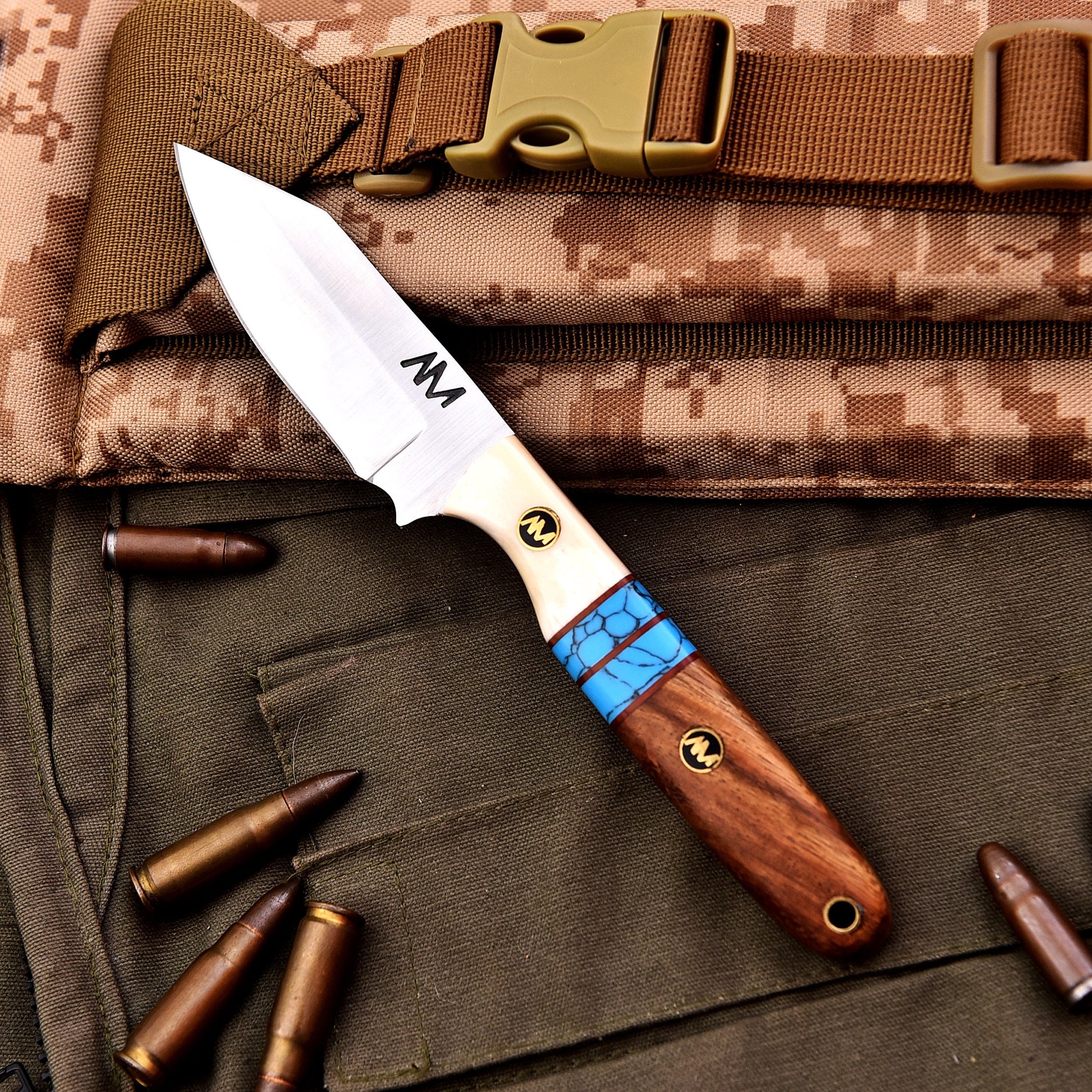 Knife with a wooden handle and blue accent on camouflage fabric with bullets
