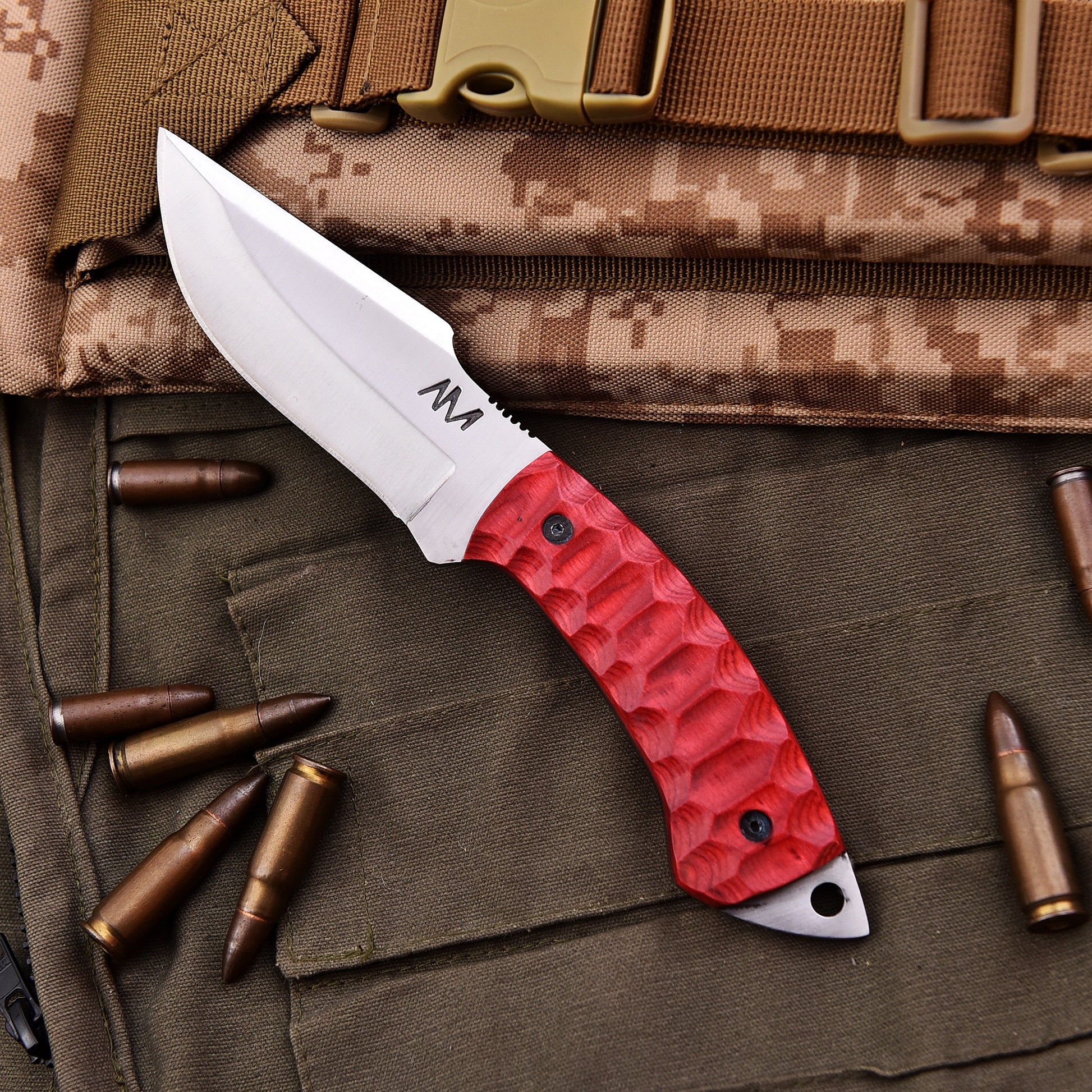 Red-handled knife on a camouflage surface with bullets