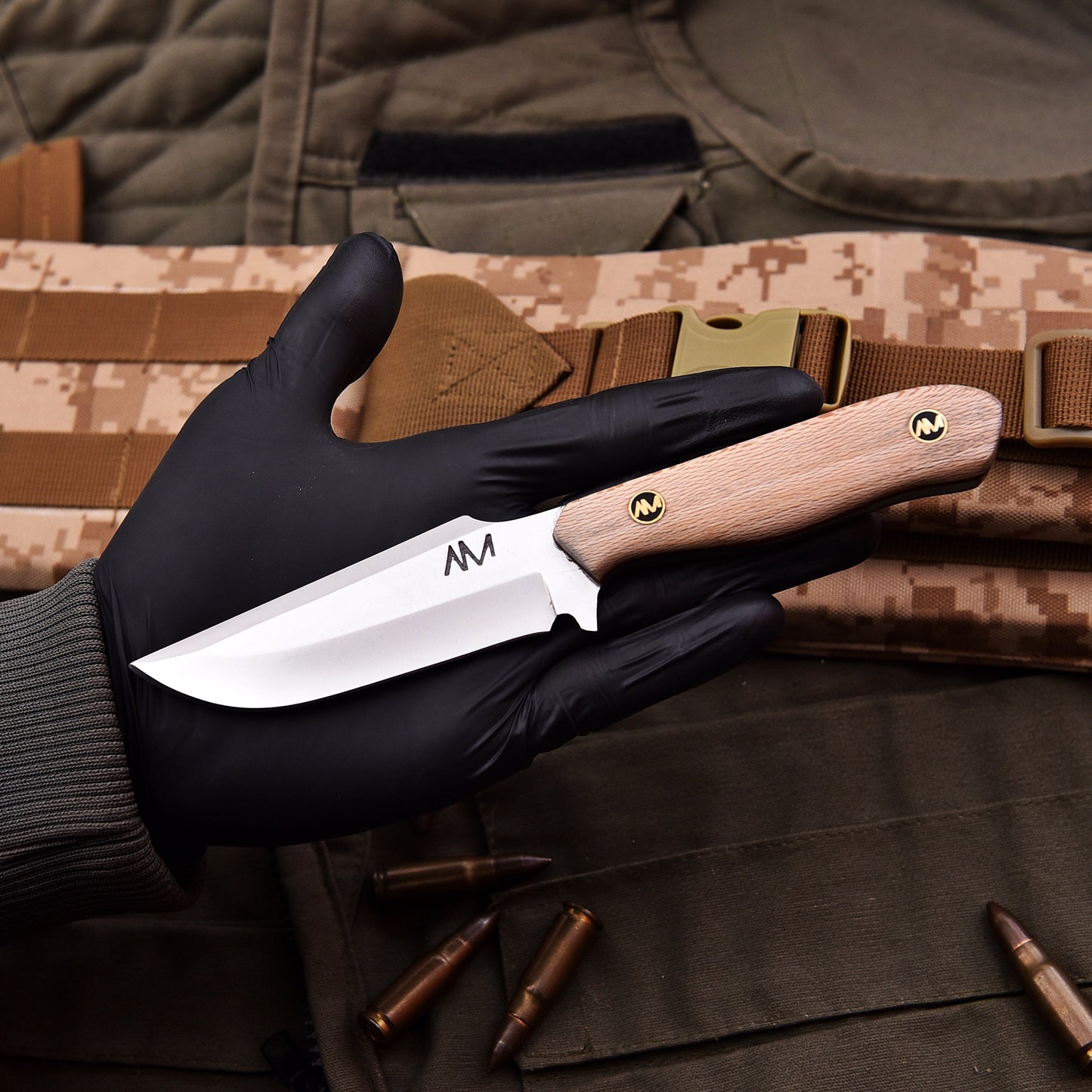 Hand holding a knife with a wooden handle against a camouflage background