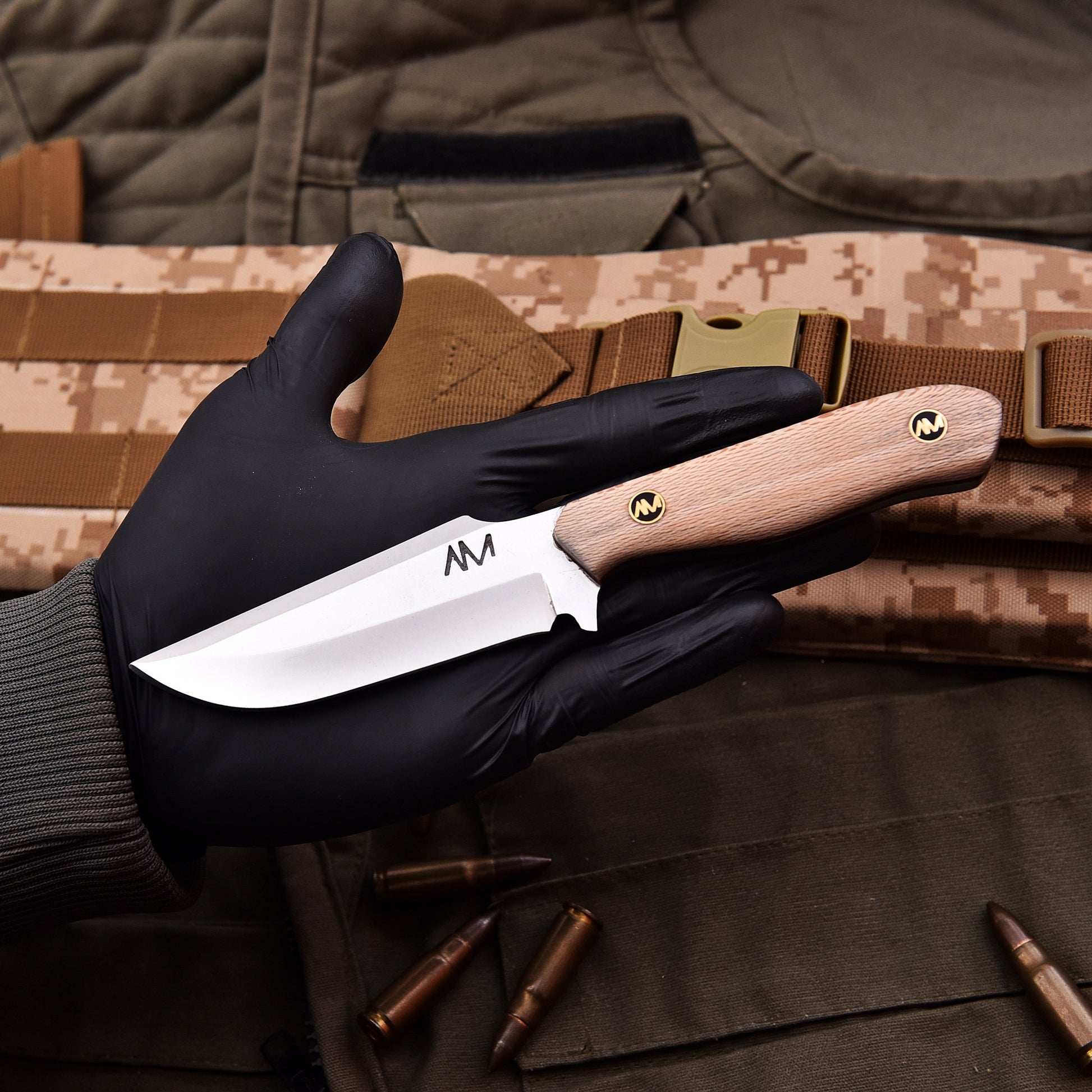 Hand holding a knife with a wooden handle against a camouflage background