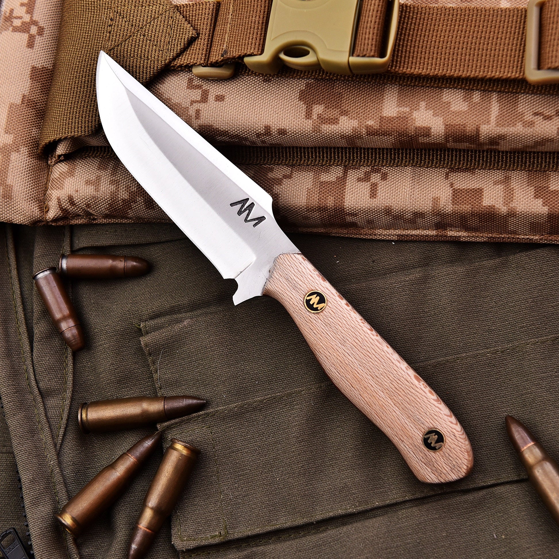 Knife with wooden handle on camouflage fabric with bullets
