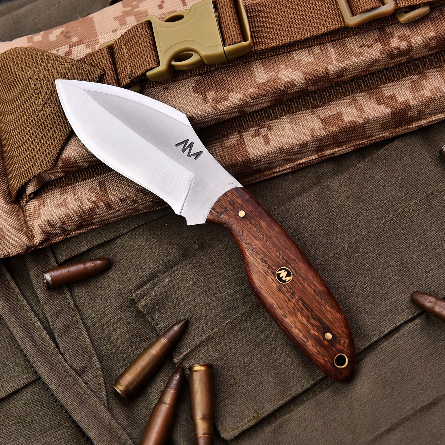 Knife with wooden handle on camouflage fabric background