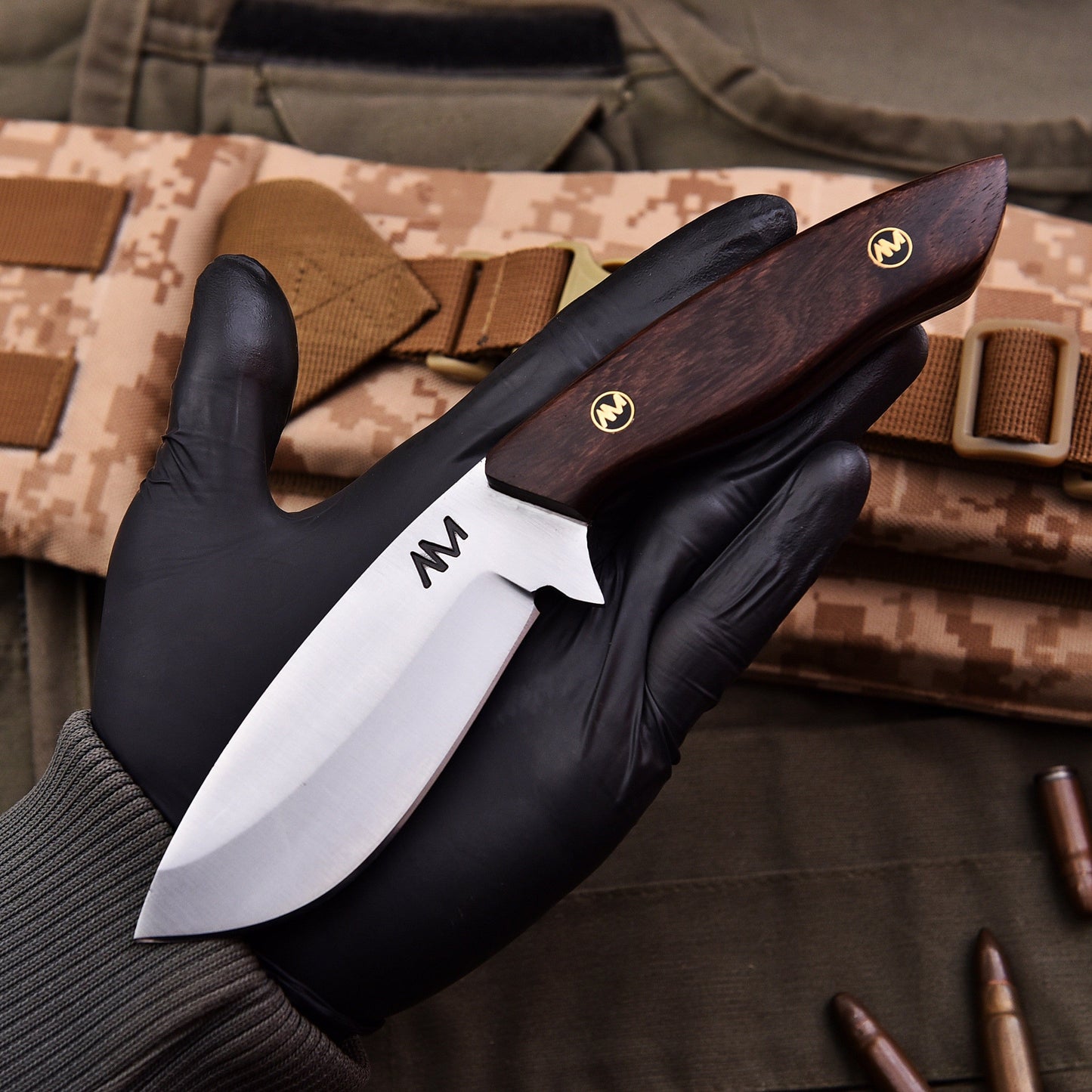 Knife held by a gloved hand with camouflage background