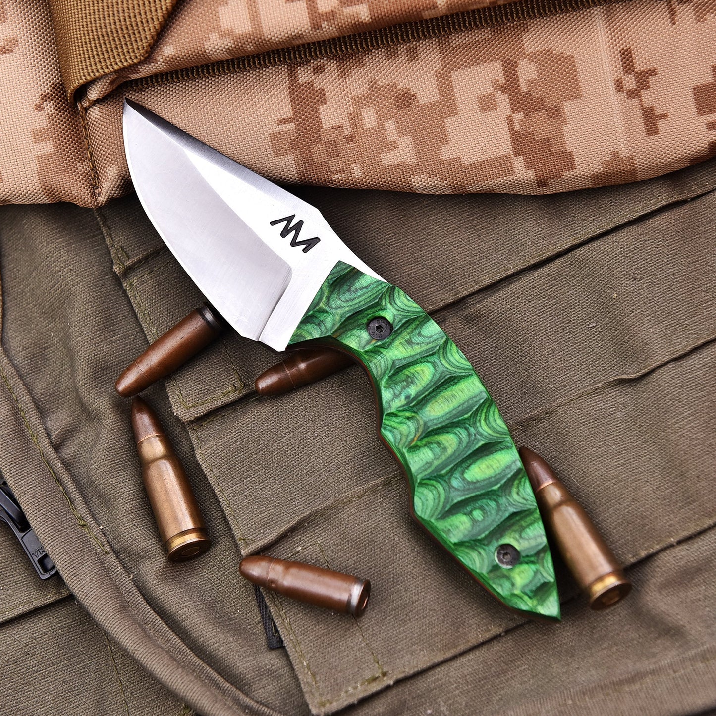 Knife with green handle and silver blade on a camouflage surface