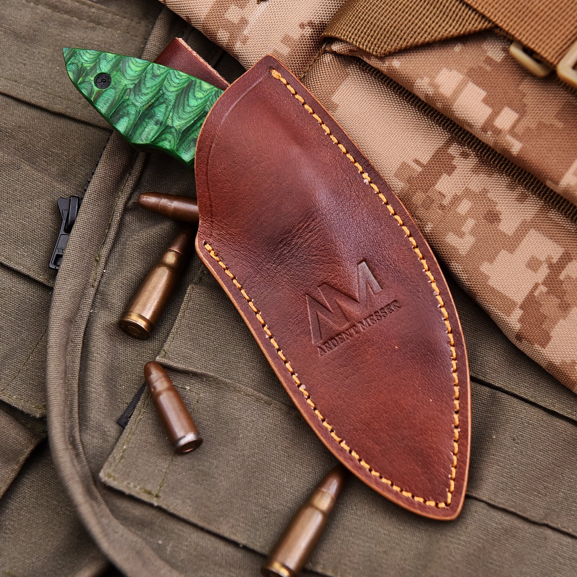 Brown leather knife sheath with green blade on camouflage fabric