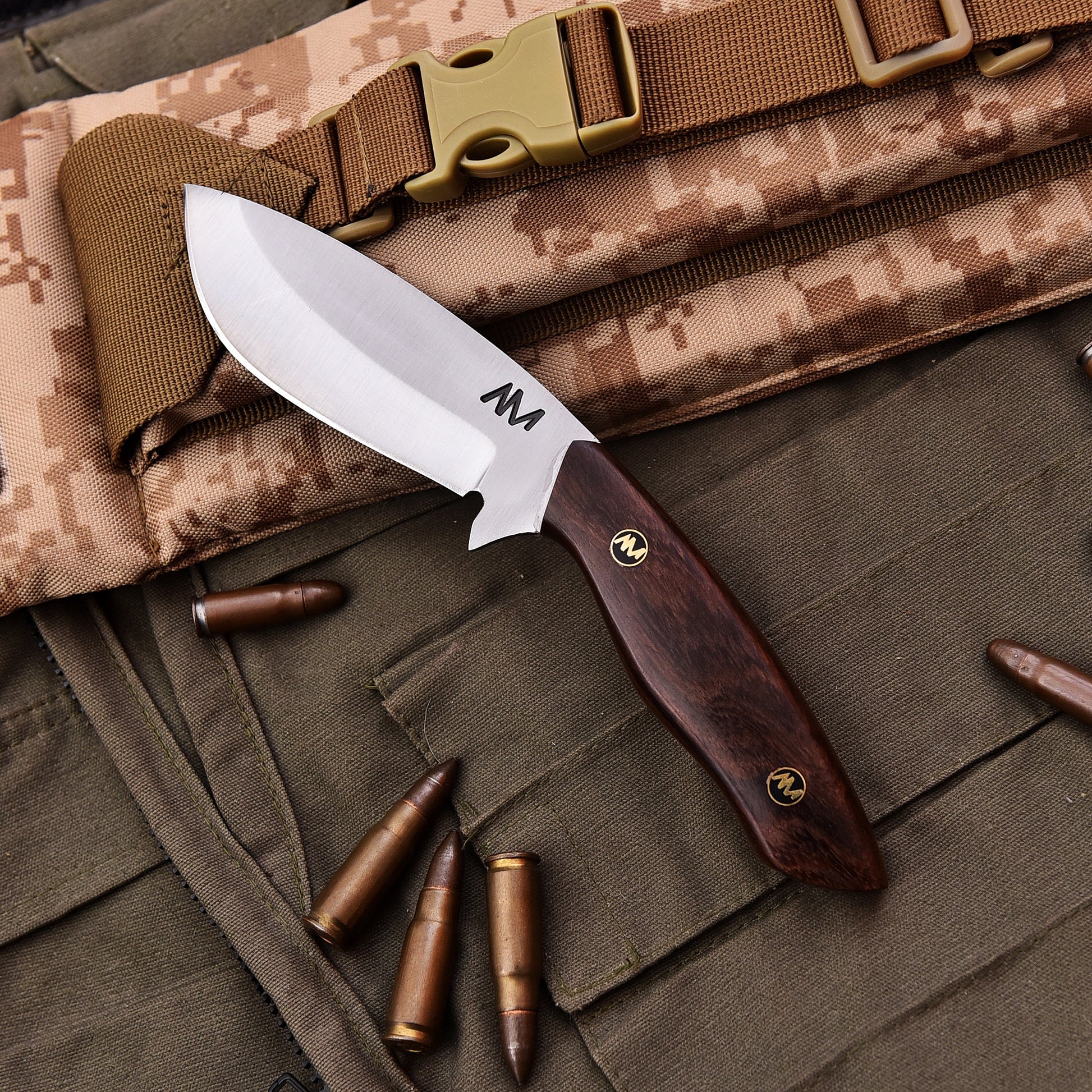 Knife with wooden handle on camouflage fabric with bullets