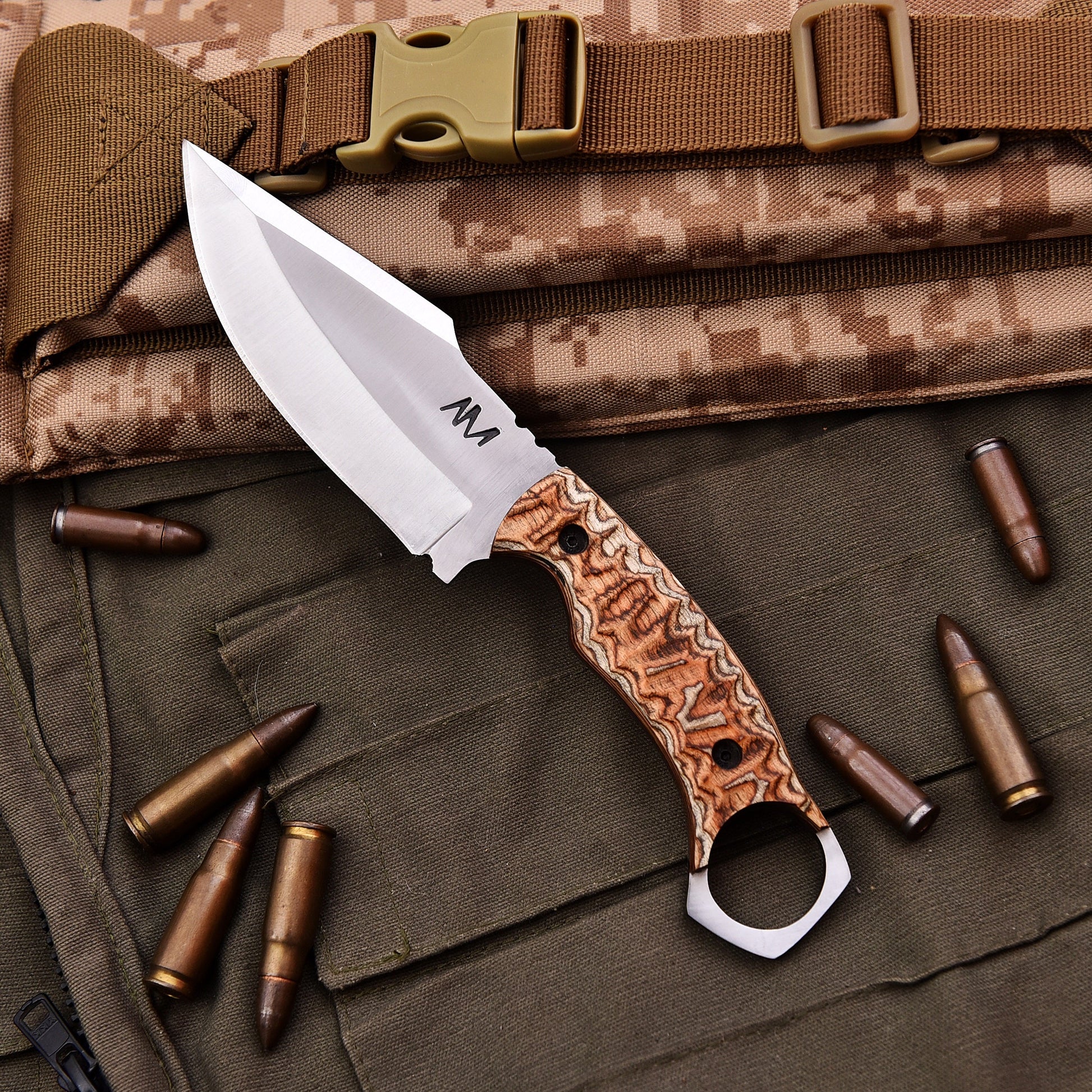 Knife with a decorative handle on a camouflage surface with bullets