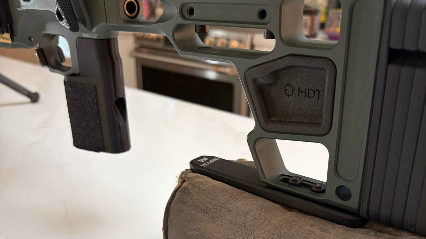 Close-up of a rifle stock and scope on a white surface