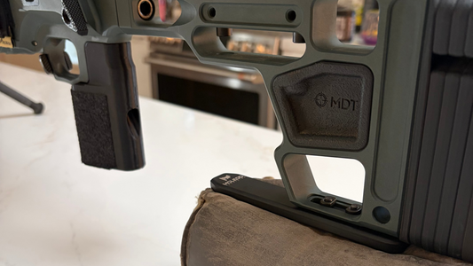 Close-up of a rifle stock and scope on a white surface