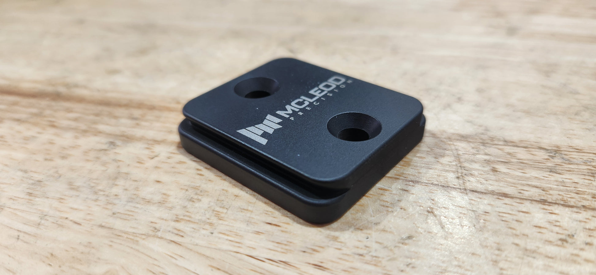 Black metal bracket with 'Nikon' branding on a wooden surface