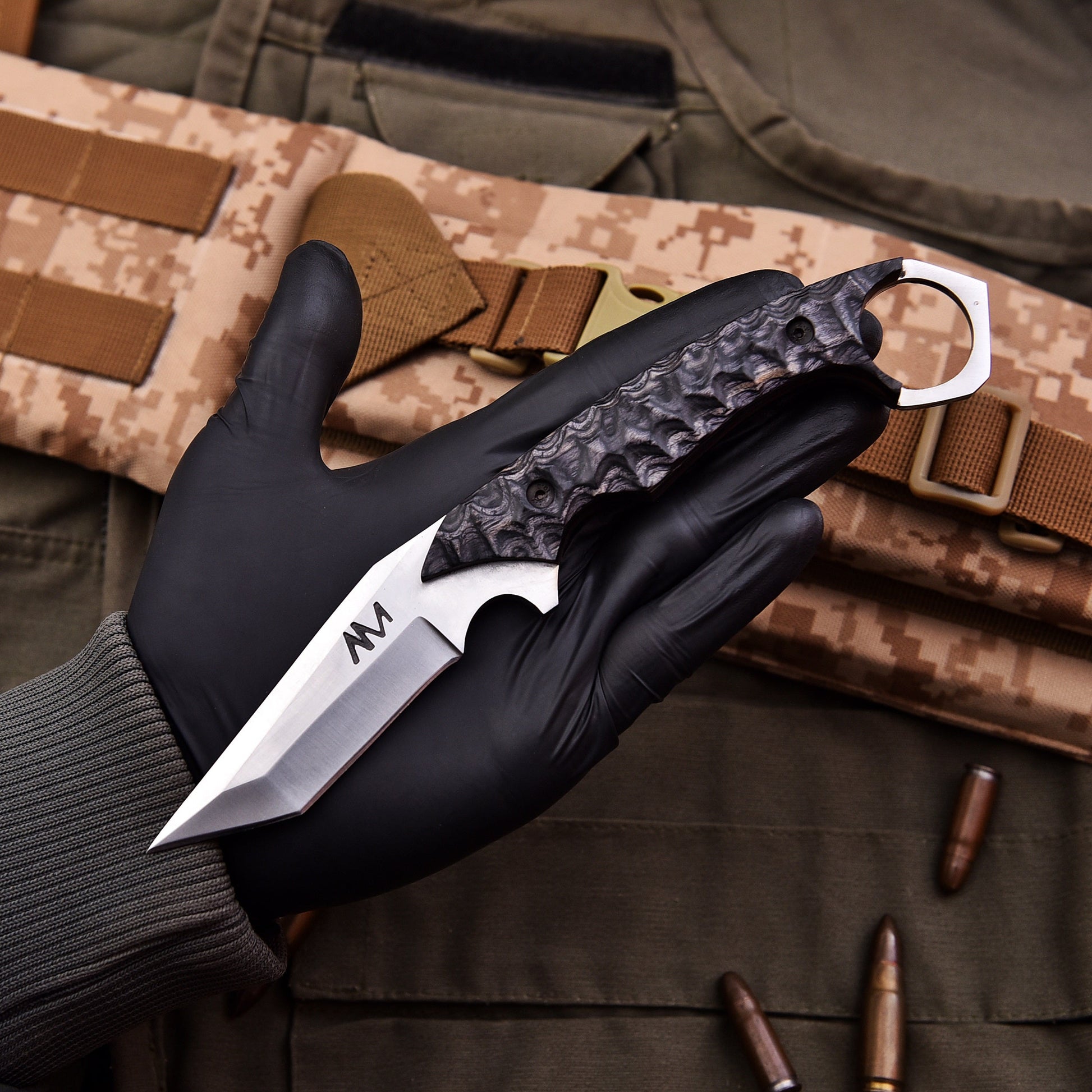Black gloved hand holding a knife with a tactical background
